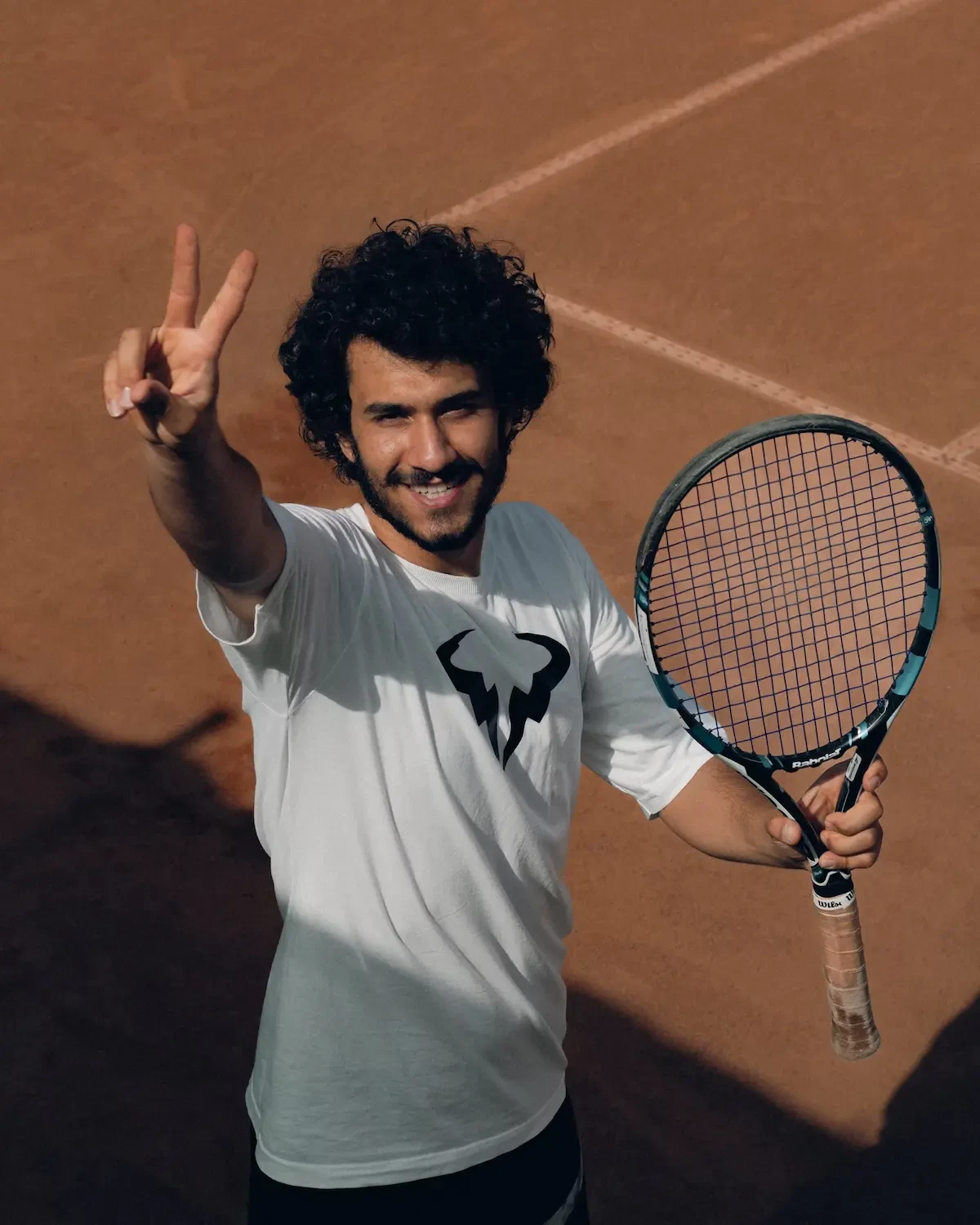 Met met tennisracket maakt V-gebaar